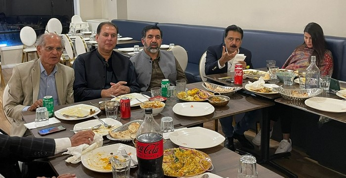 A group of men sitting at a table with food

Description automatically generated